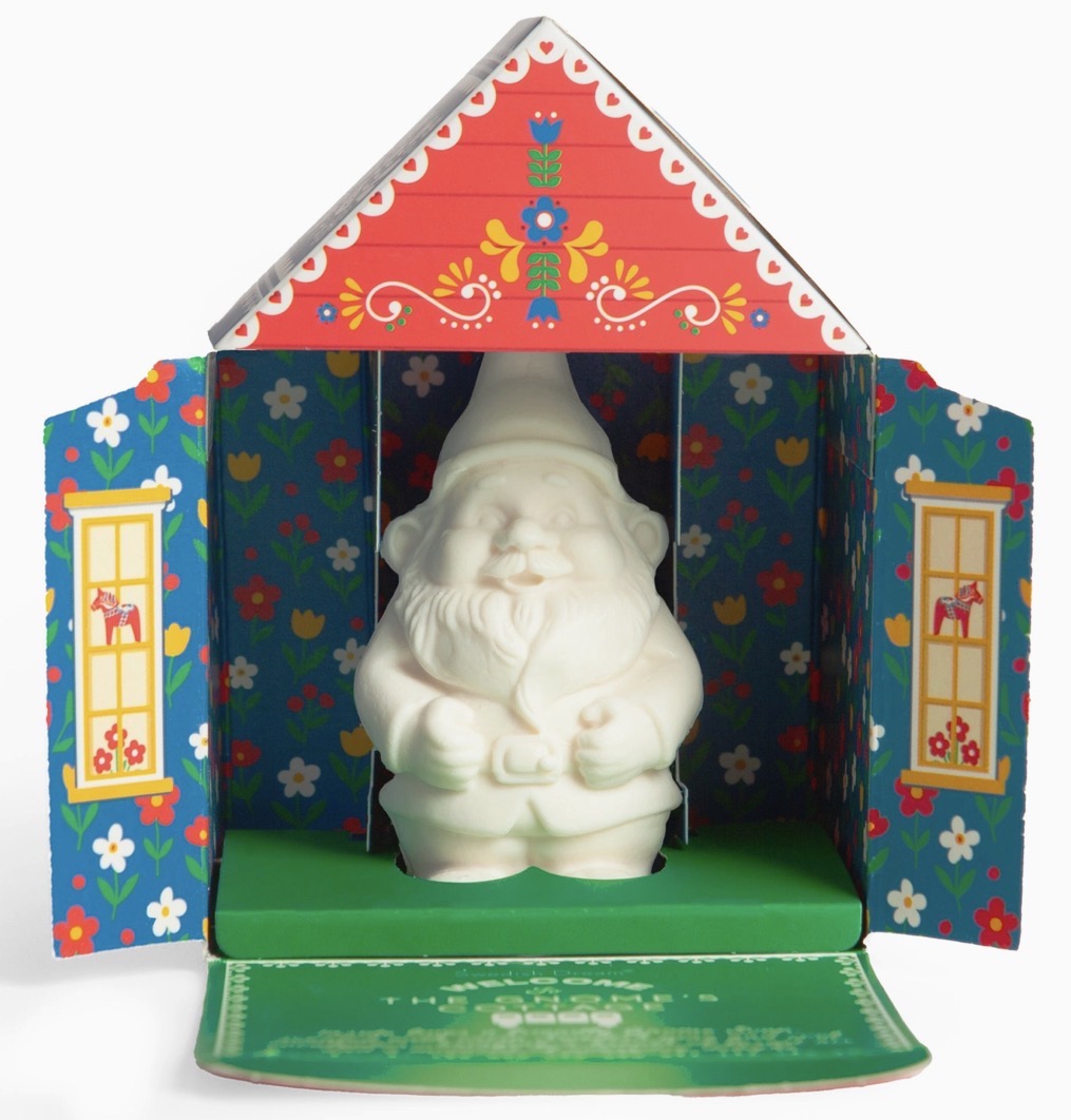 A white ceramic Santa Claus ornament displayed inside a colorful decorative house-shaped presentation box with a red roof and floral blue sides.