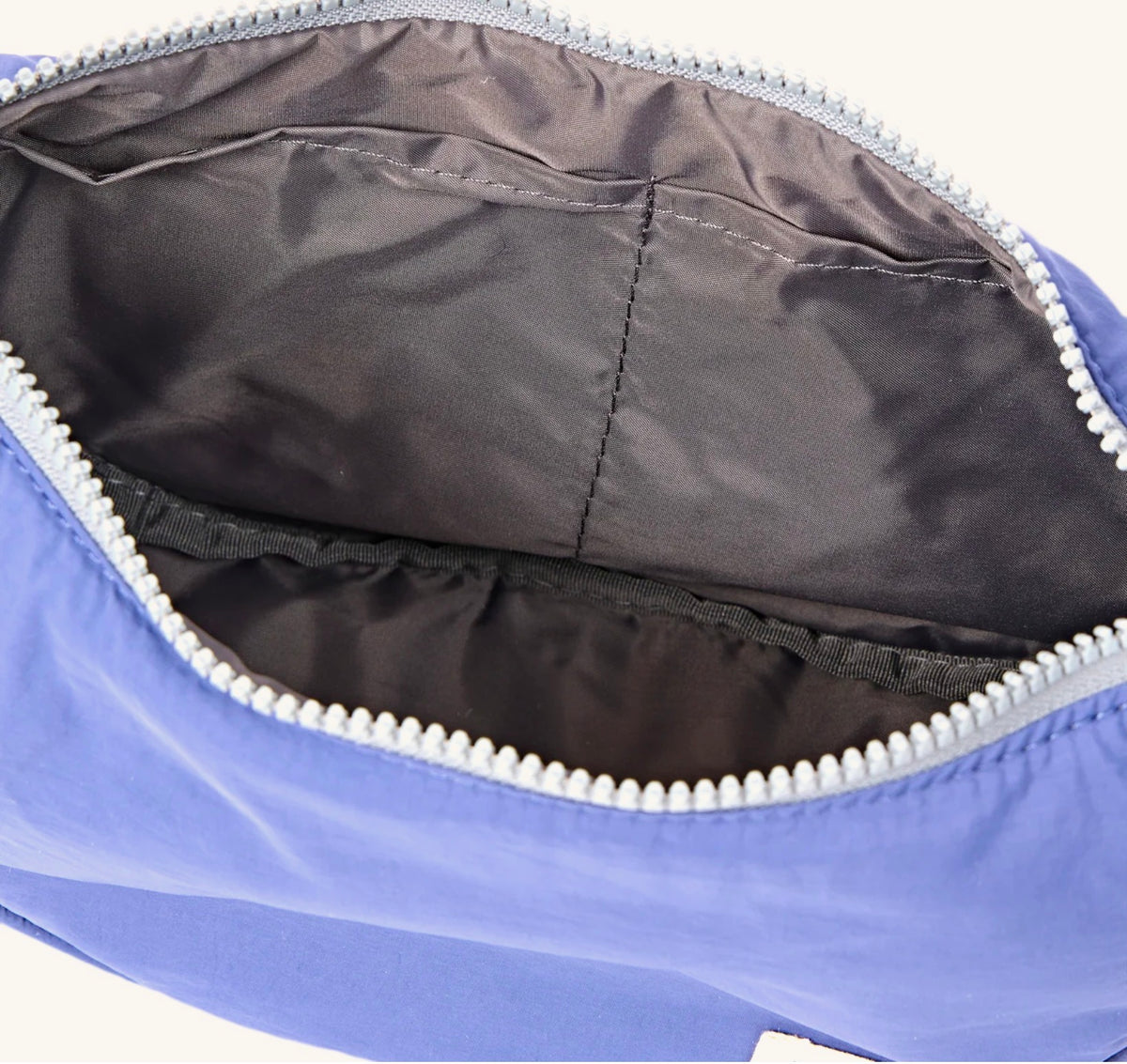 Close-up of the interior of a blue zippered pouch or bag, showing a dark gray fabric lining and a white zipper.