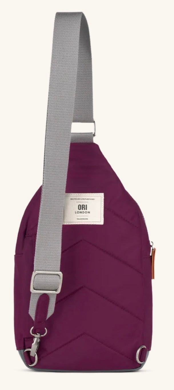 A plum purple sling bag with a gray adjustable shoulder strap and a white brand label that reads 'ORI LONDON'.