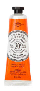 A squeeze tube of La Montagne Fleur Doranger hand cream in the Orange Blossom scent, featuring a bright orange body with a black cap and a white central label.