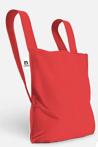 A red canvas tote bag with a subtle grid pattern and dual shoulder straps, shown on a light gray background. A small white brand tag on the side displays the logo for 'nasaquo'.
