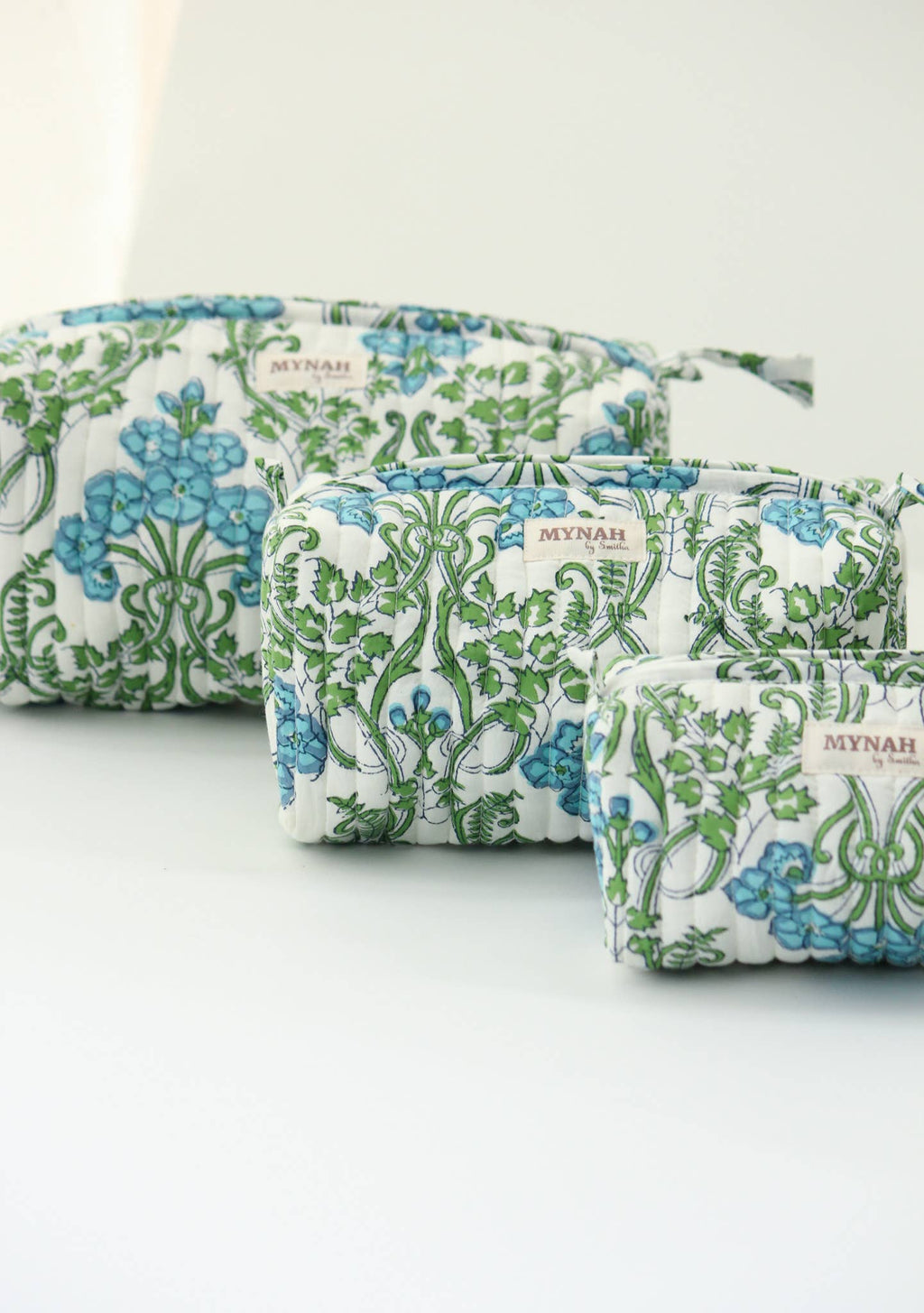 Three quilted fabric pouches with a white background and a green and blue floral vine pattern, arranged diagonally on a white surface. The pouches feature a small woven label reading 'MYNDAH'.