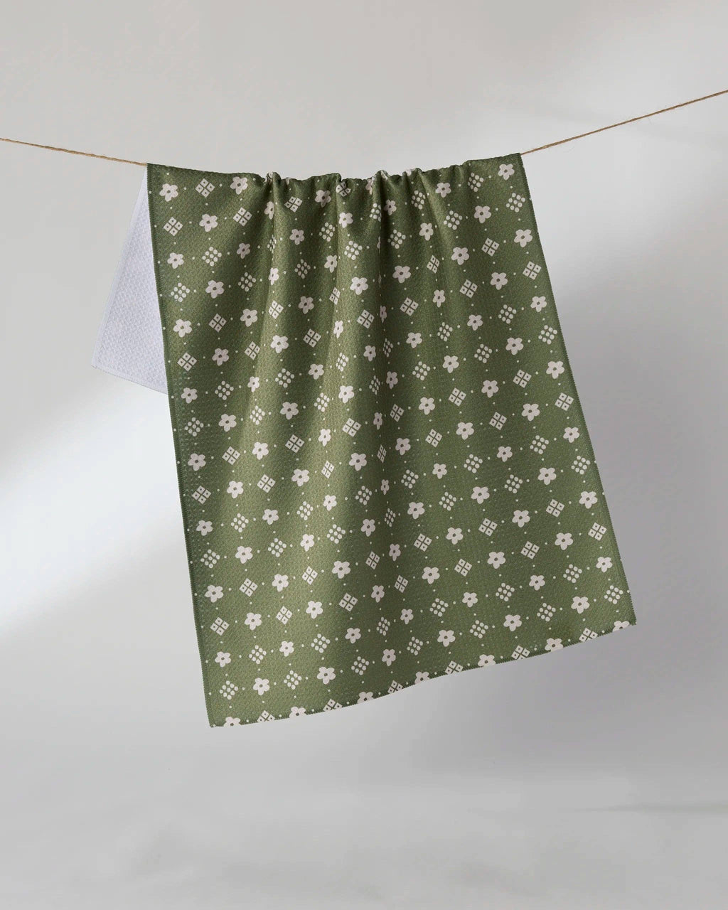 An olive green curtain panel with a repeating white floral and geometric pattern, hanging from a thin wire against a neutral gray background.