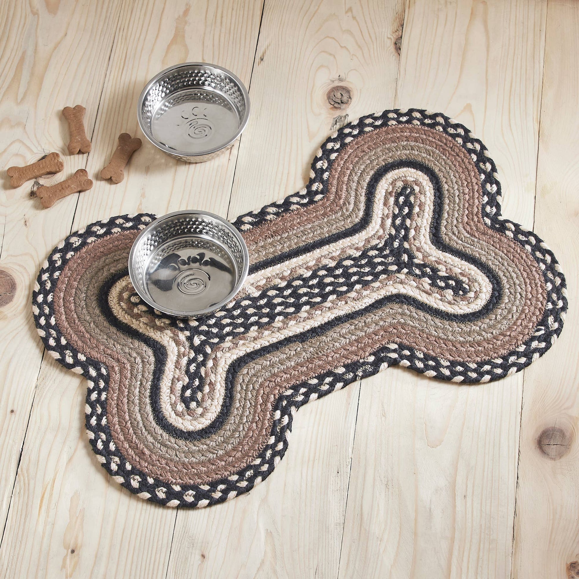 Dog bone-shaped mat with two metal bowls on a wooden floor.