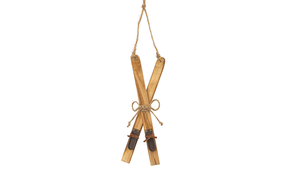 A decorative hanging ornament shaped like a pair of crossed wooden skis tied with twine, suspended by a rope against a plain white background.