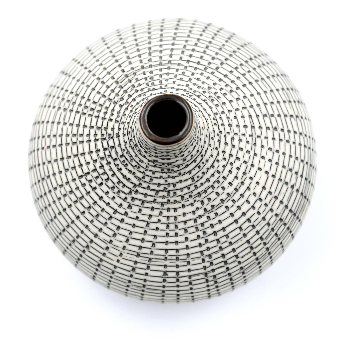 A top-down view of a round, conical ceramic vase with a white glaze and a black geometric grid pattern, set against a plain white background.