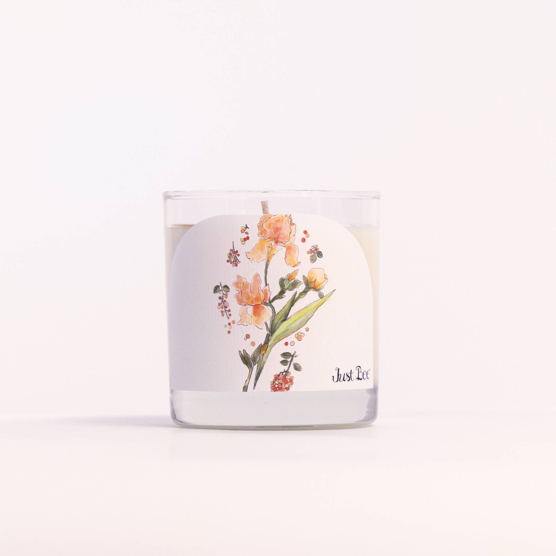 A clear glass jar candle with white wax and a white label featuring a watercolor illustration of yellow and orange flowers with green leaves. The brand name 'Just Et' is printed in black script on the lower right of the label.