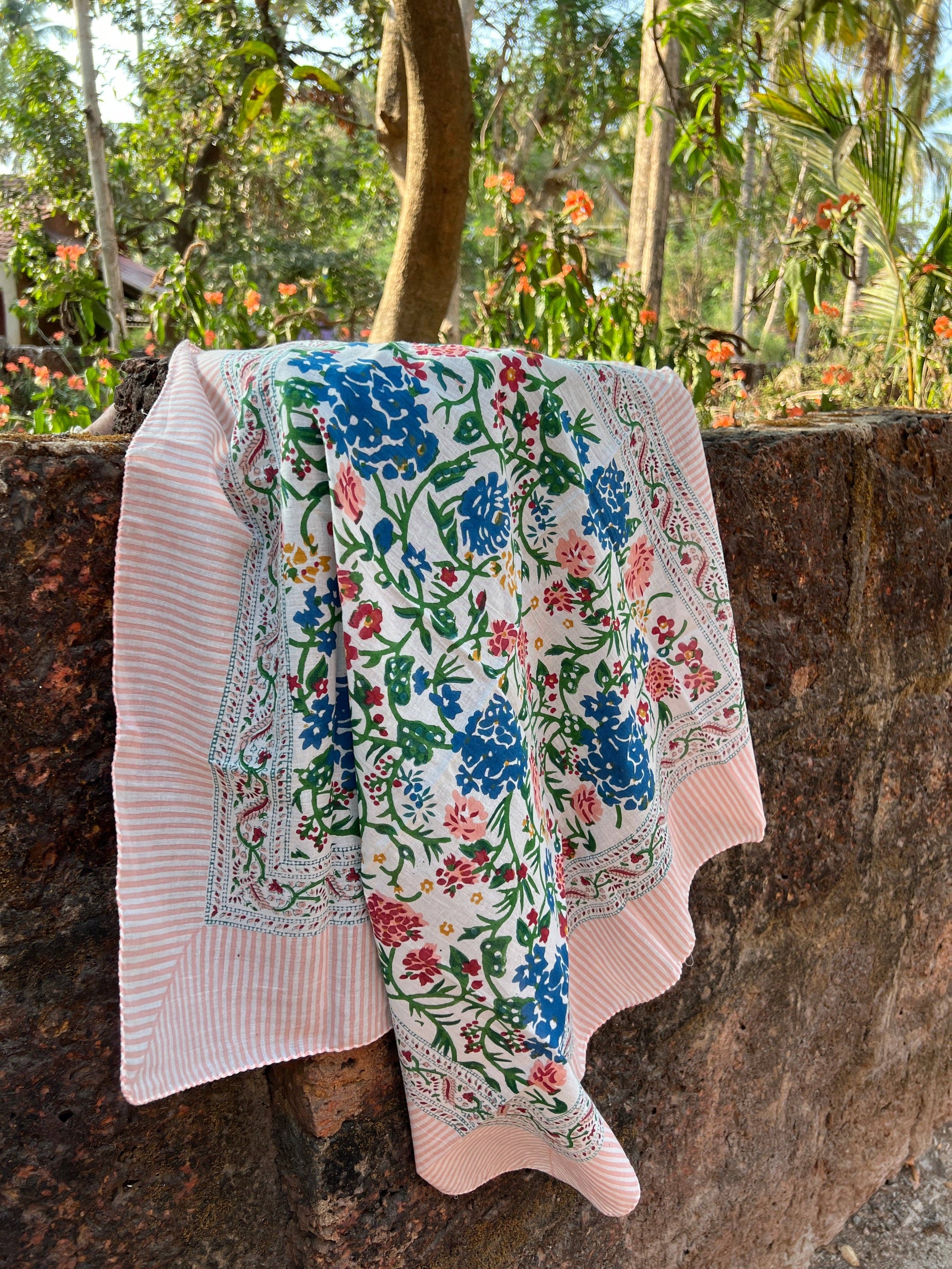 Floral-patterned fabric draped over a stone wall with a garden background