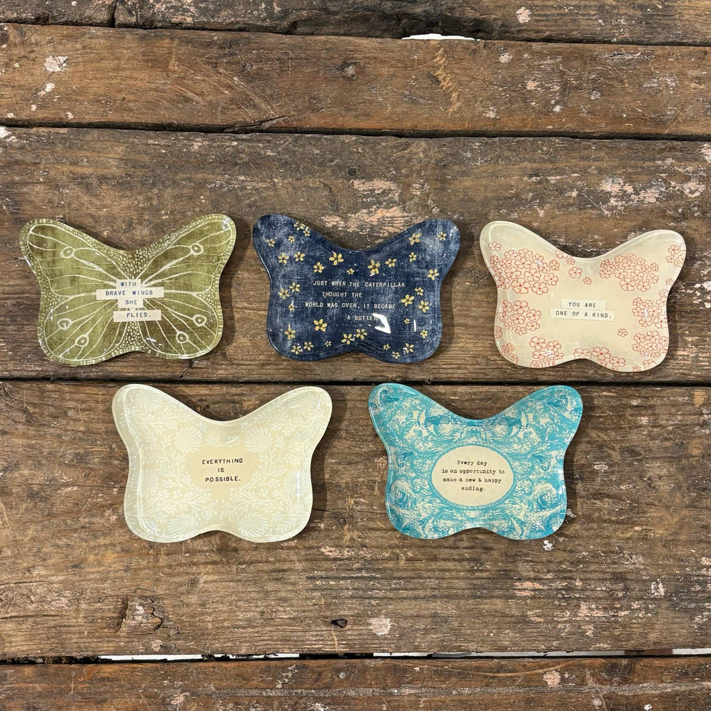 Five butterfly-shaped coasters with printed designs on a wooden surface
