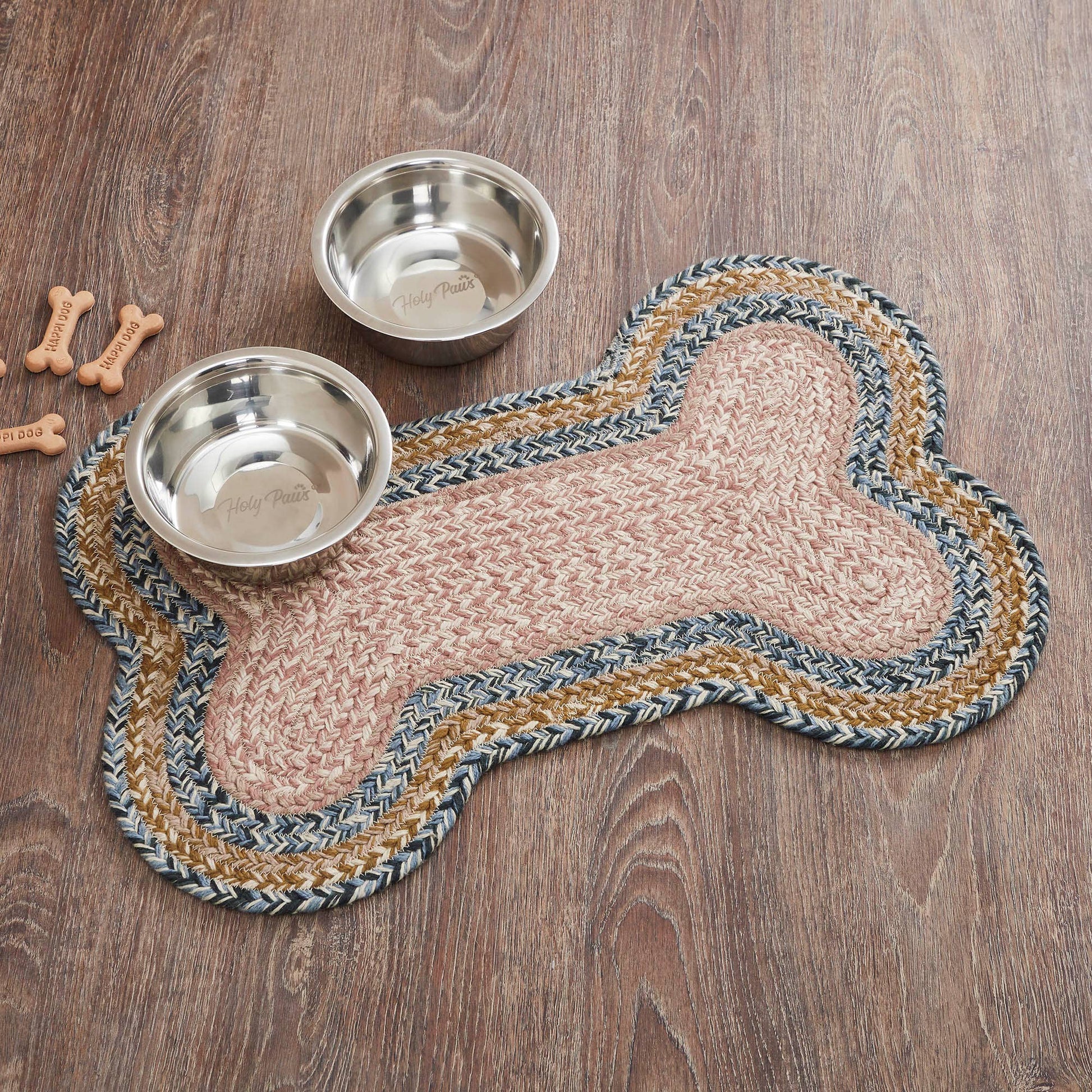 Dog bone-shaped mat with two metal bowls on a wooden surface.