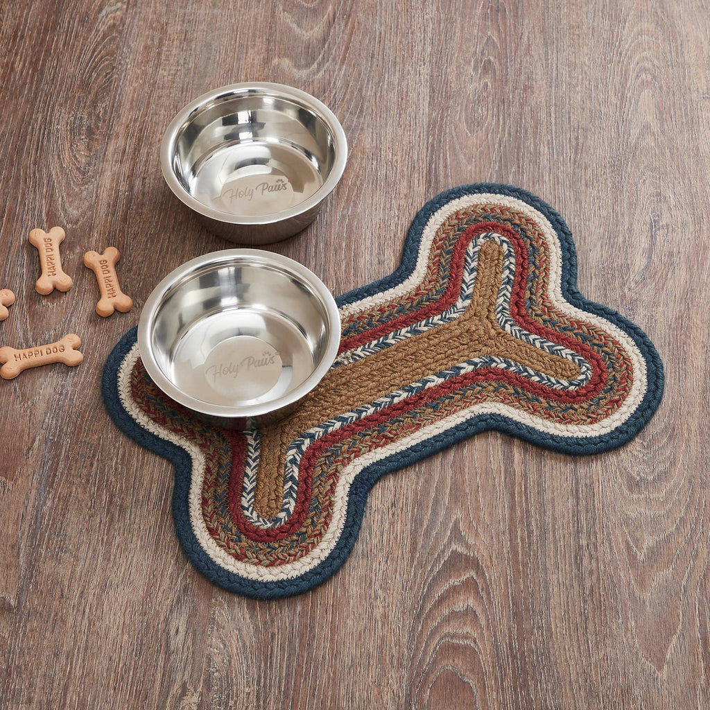 Two metal dog bowls on a bone-shaped mat with dog bones on a wooden surface