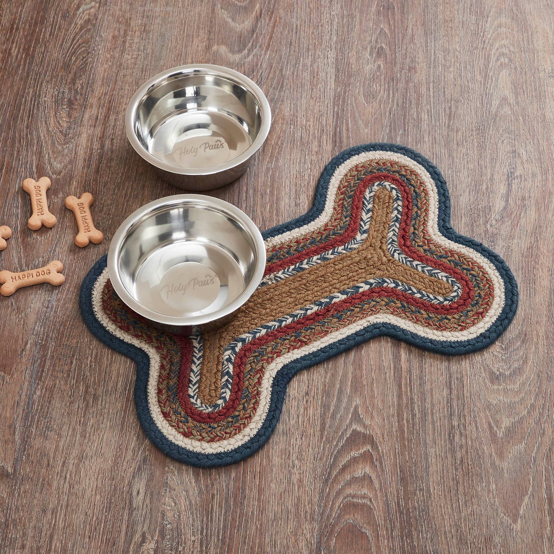 Two metal dog bowls on a bone-shaped mat with dog bones on a wooden surface
