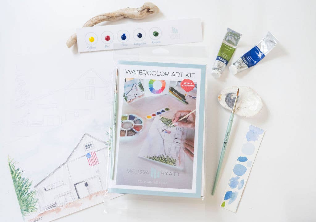 A watercolor art kit laid out on a white surface, including a box labeled 'WATERCOLOR ART KIT' by Melissa Hyatt, paint tubes, a palette, brushes, paper swatches, and a small printed house illustration.