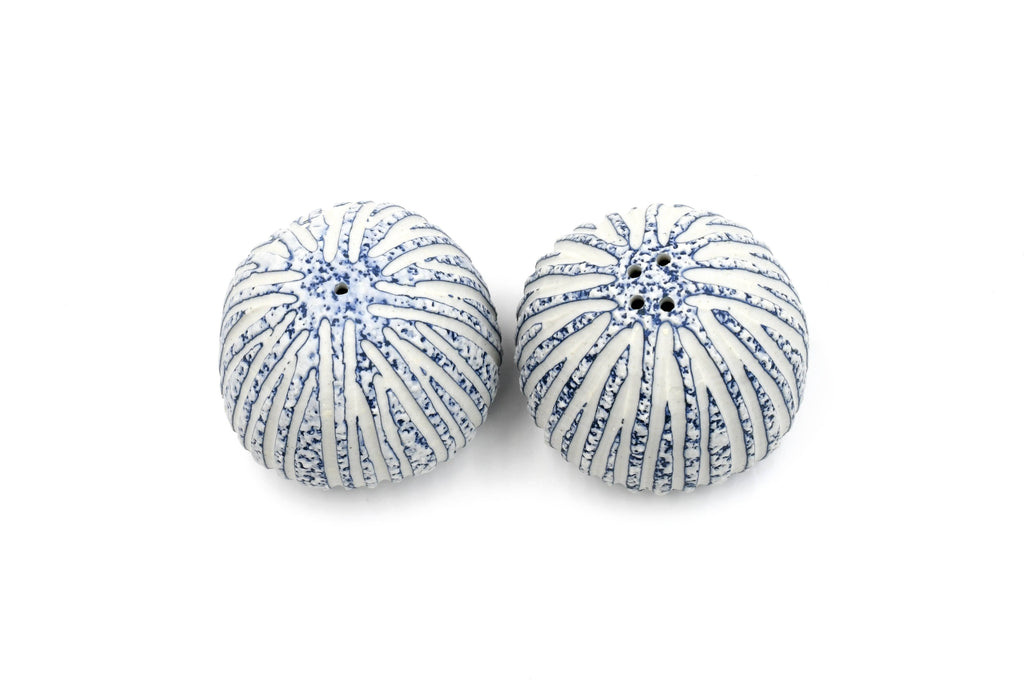 A pair of round, ribbed decorative pumpkins or gourds with a white base and blue speckled stripe pattern, shown on a plain white background.