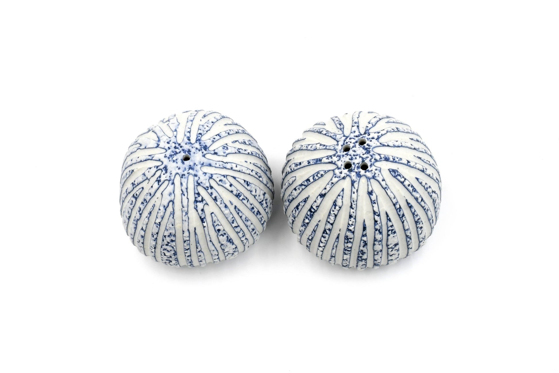 A pair of round, ribbed decorative pumpkins or gourds with a white base and blue speckled stripe pattern, shown on a plain white background.