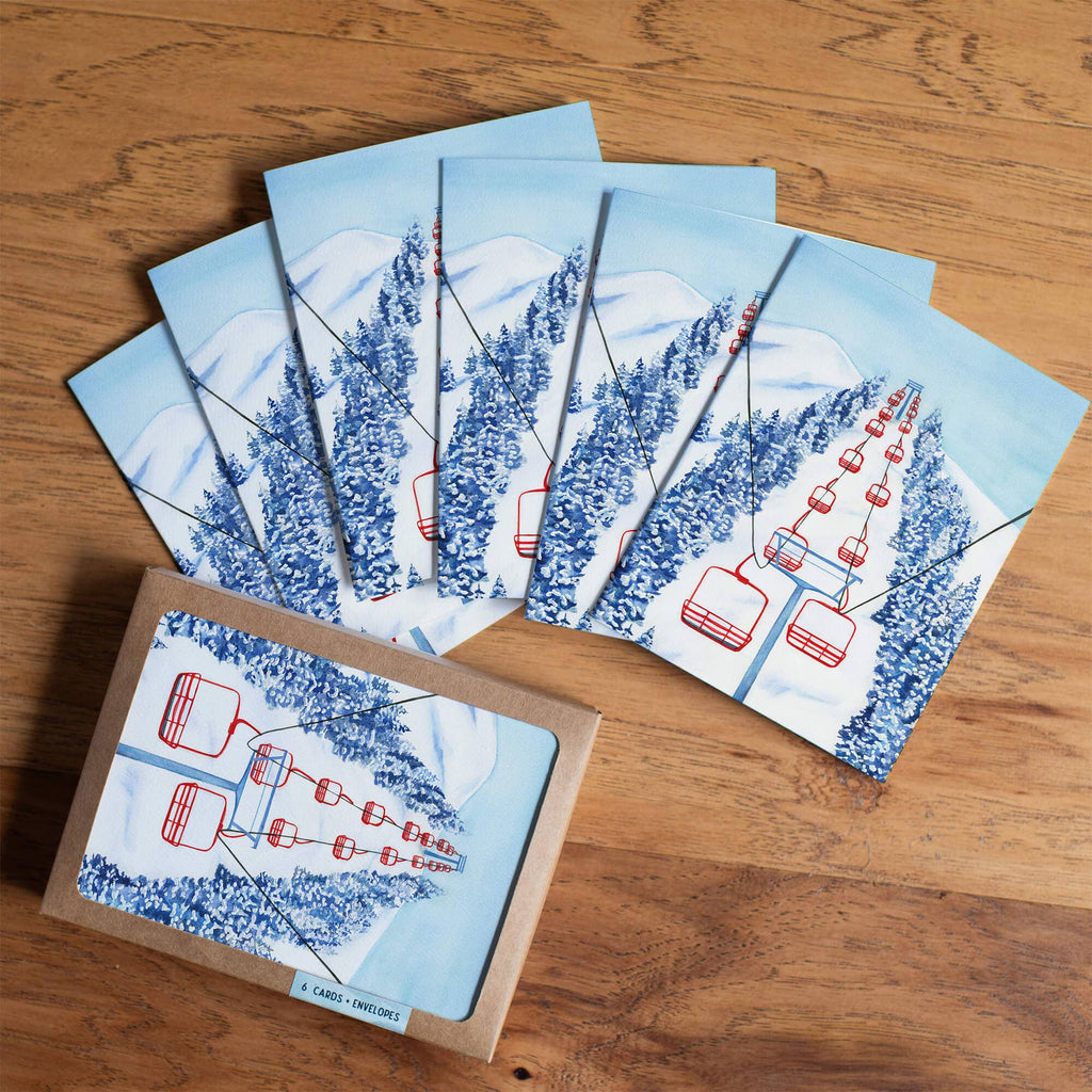 Set of greeting cards with ski lift design on a wooden surface