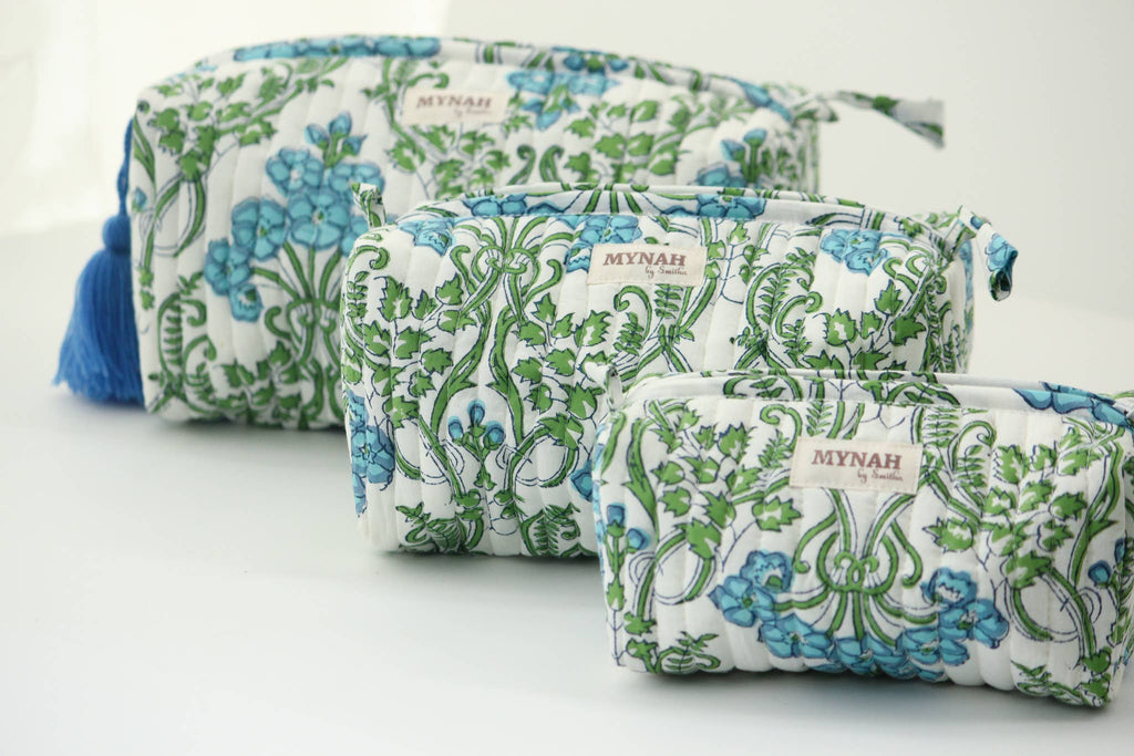 Three quilted cosmetic pouches in a size gradient, featuring a white background with a green and blue floral vine pattern. The largest pouch has a blue tassel on the side, and each pouch has a small 'MYNAH' brand label on the front.