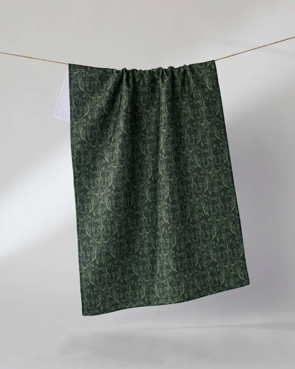 Green patterned fabric hanging on a line against a white background