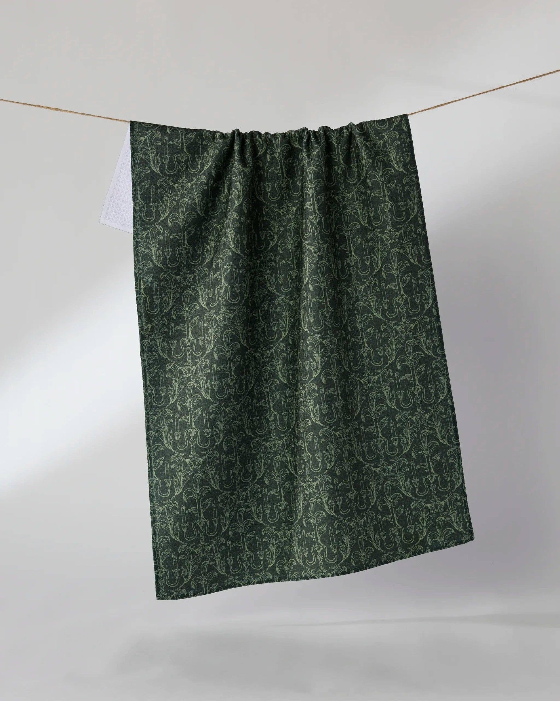Green patterned fabric hanging on a line against a white background