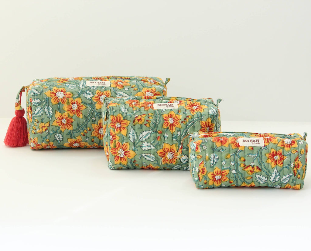 Set of three floral-patterned pouches with tassels on a light gray background