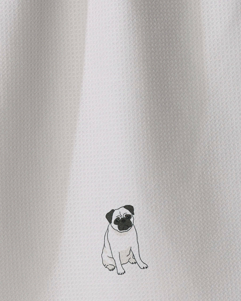 Close-up of a white textured fabric with a small black line-art illustration of a pug near the bottom center.