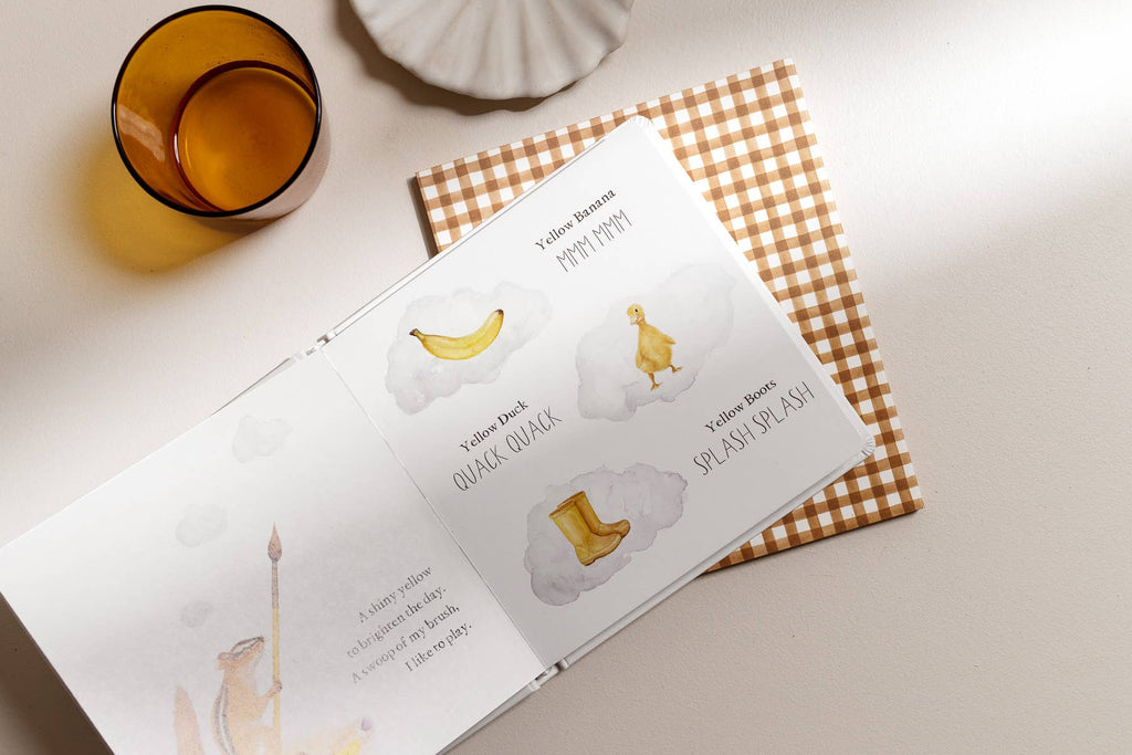 Open book with illustrations of a banana, cloud, and boot on a checkered fabric background.