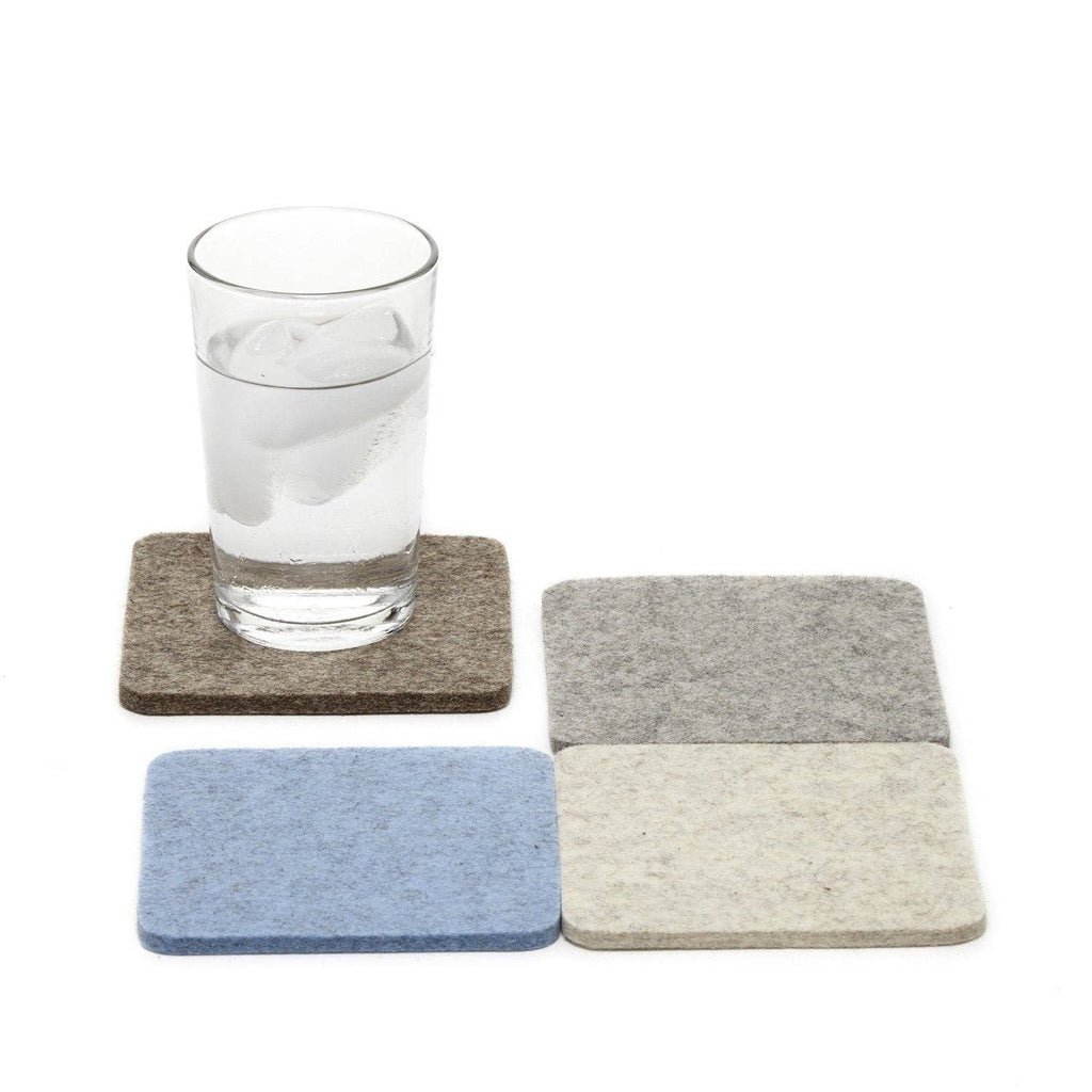 Set of square coasters in gray, blue, and beige with a glass of water on one coaster.