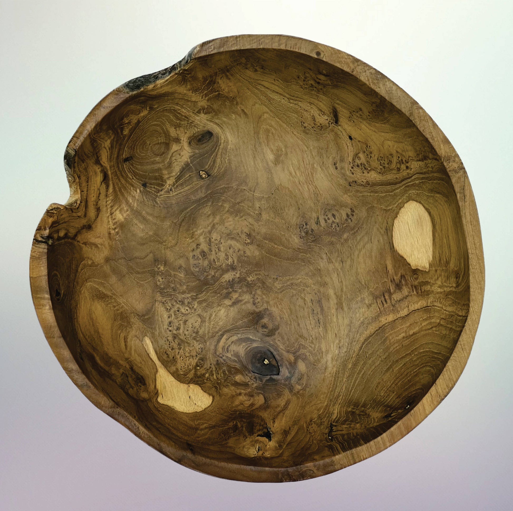 A handcrafted wooden bowl with a natural live edge and rich swirling grain patterns, photographed from directly above against a light gray gradient background.